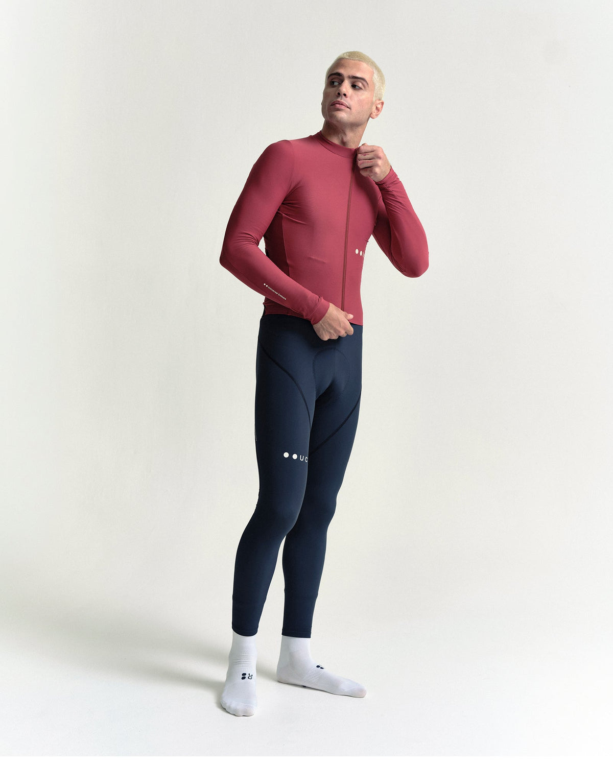 Model zipping the Men's Mono Long Sleeve Jersey in Apple Red, full-length view.