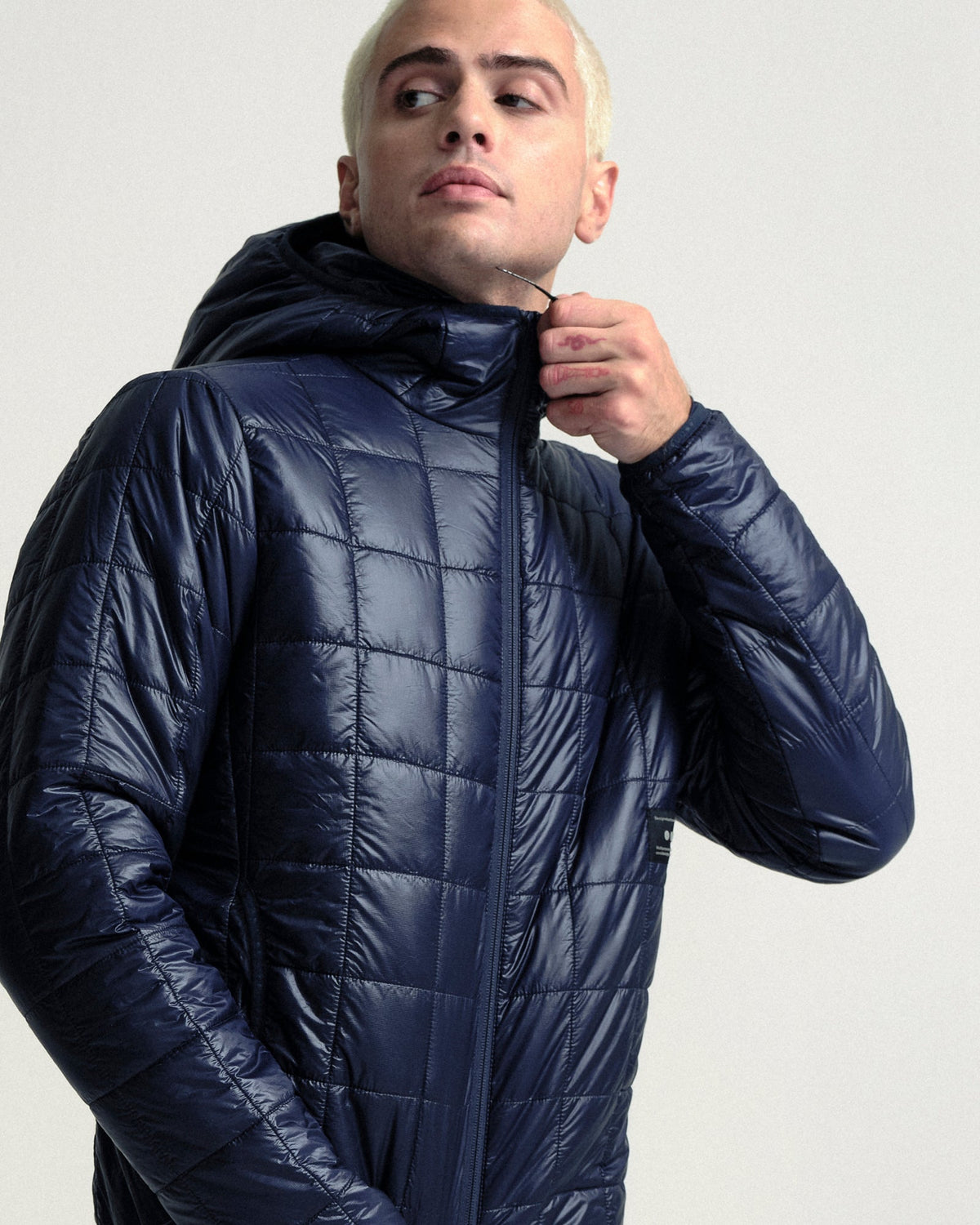 Model wearing the Unisex Insulated Packable Jacket in Ink Blue.