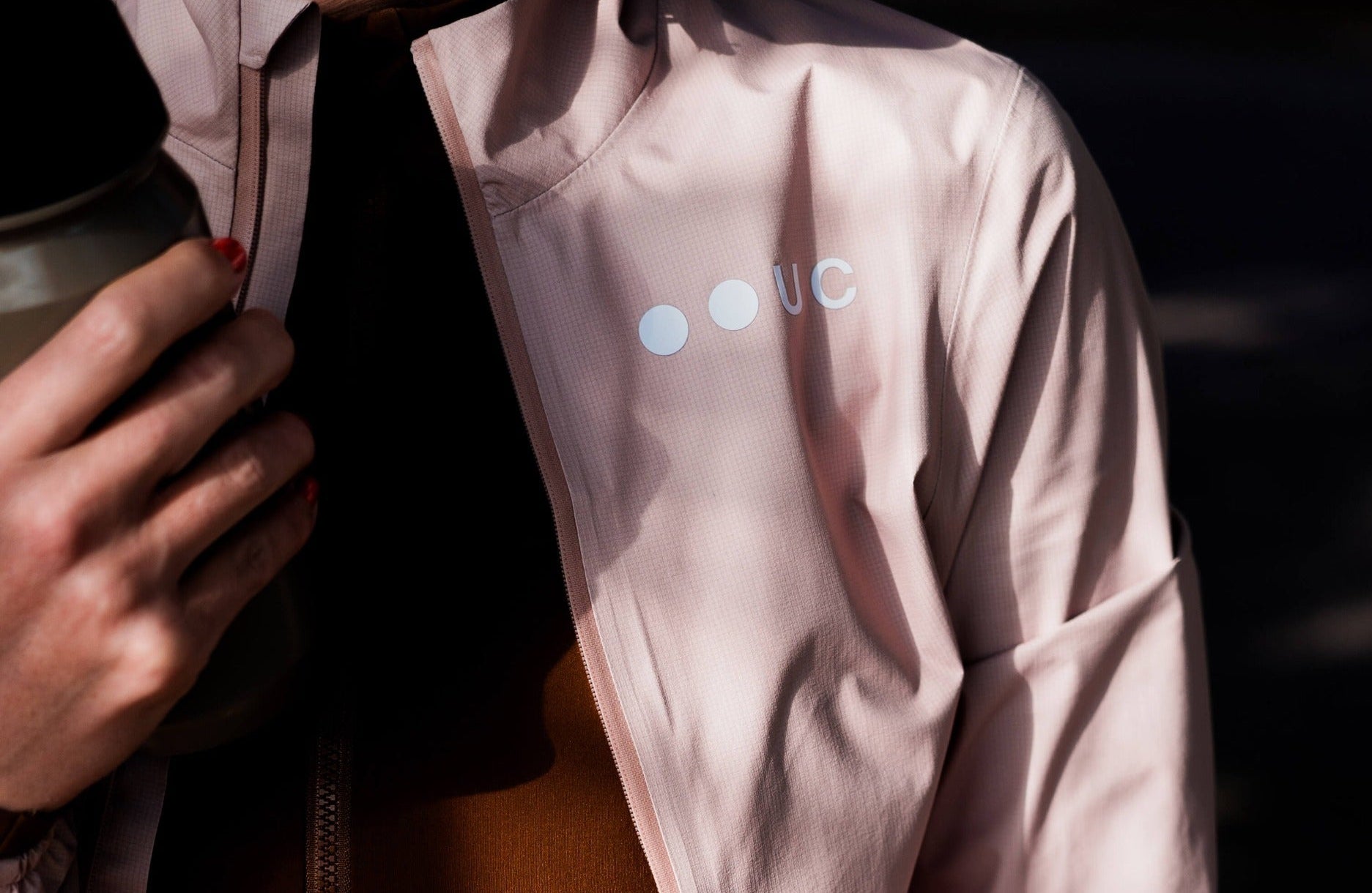 Woman wearing a Universal Colours cycling jacket with visible reflective elements.