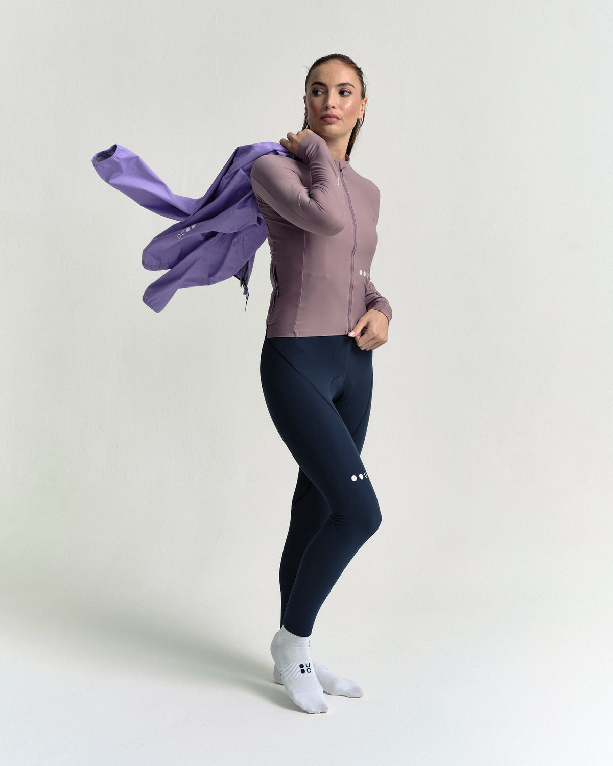 Model swinging the Women's Mono Rain Jacket in Cloud Lilac on over her shoulder.